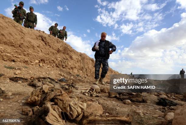 Members of the Kurdish forces look at the remains of Yazidis killed by the Islamic State jihadist group as they search for clues that might lead them...