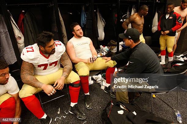 Head Coach Jim Harbaugh of the San Francisco 49ers talks with Mike Iupati and Joe Staley in the locker room following the game against the Carolina...