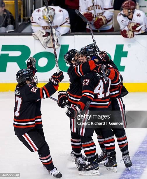 Dustin Darou of the Northeastern Huskies celebrates his game winning goal with teammate Matt Benning, Dalen Hedges and Kevin Roy during NCAA hockey...