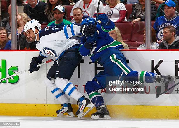 Dustin Byfuglien of the Winnipeg Jets checks Luca Sbisa of the Vancouver Canucks during their NHL game at Rogers Arena February 3, 2015 in Vancouver,...