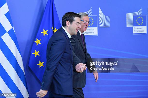 Greek Prime Minister Alexis Tsipras holds hands with European Commission President Jean-Claude Juncker at the European Commission headquarters in...