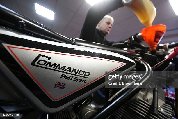 Made In England" logo sits on the gas tank of a Norton Commando 961 Sport motorbike, produced by Norton Motorcycles Ltd., as an employee pours motor...