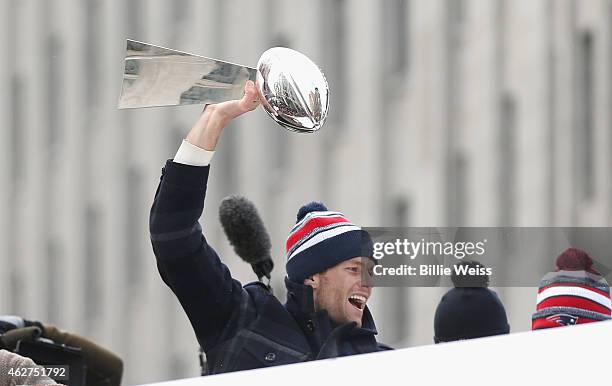 Quarterback Tom Brady of the New England Patriots hoists the Vince Lombardi trophy during a Super Bowl victory parade on February 4, 2015 in Boston,...