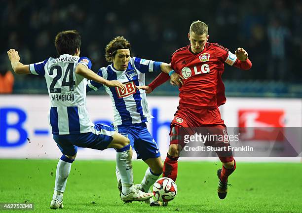 Lars Bender of Leverkusen is challenged by Hajime Hosogai and Genki Haraguchi of Berlin during the Bundesliga match between Hertha BSC and Bayer 04...
