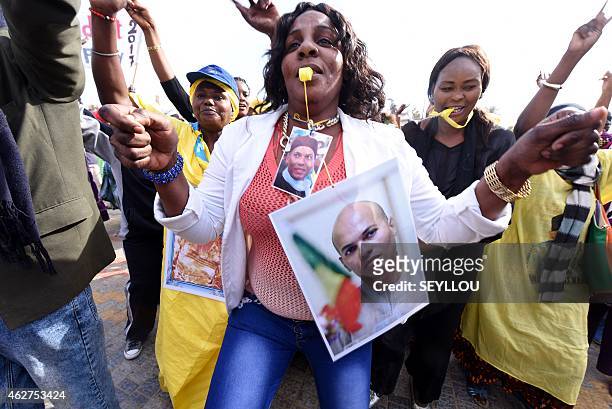 Woman dances as she wears pictures of Karim Wade, former minister and son of former Senegalese president Abdoulaye Wade, during a meeting of the...
