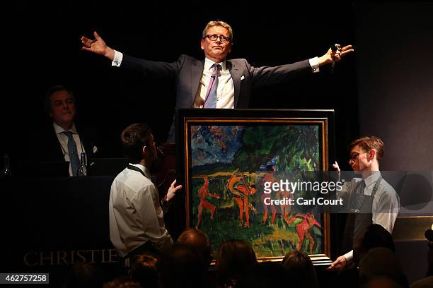 Auctioneer Jussi Pylkkanen gestures behind a painting by Erich Heckel entitled 'Badende am Waldteich' during the Impressionist and Modern Evening Art...