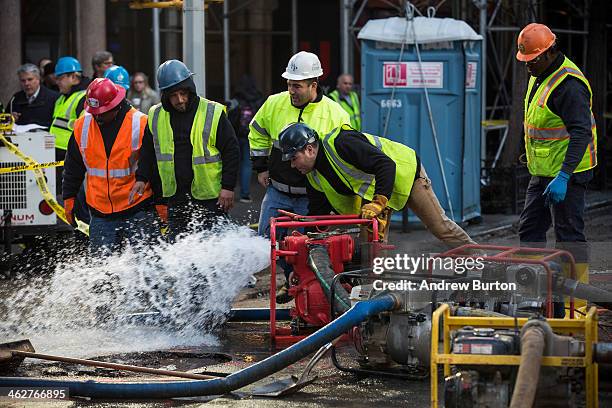 Workers use a generator to pump water out of a hole in the street, caused by a water main break on January 15, 2014 in New York City. The break...
