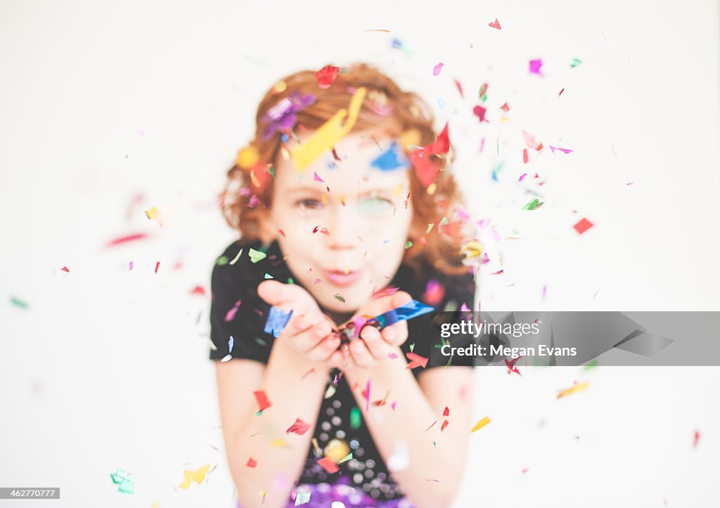 Red headed girl blowing confetti