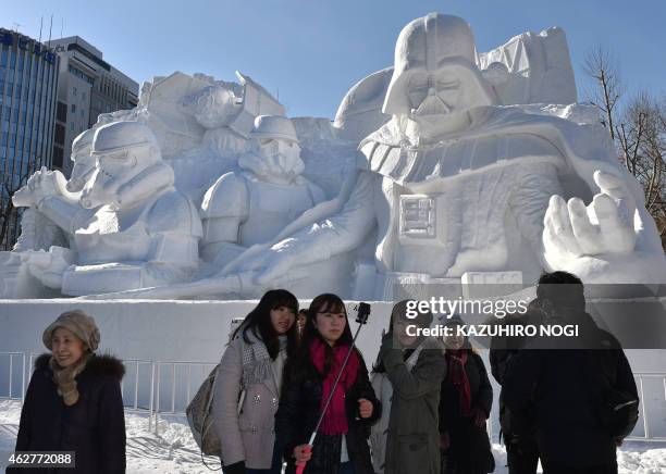 Tourists use a selfie monopod as they visit a large snow sculpture called the snow "Star Wars" made by the Japan Ground Self-Defense Force, Sapporo...