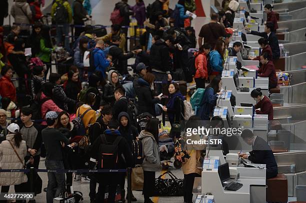 This picture taken on February 4, 2015 shows passengers checking in at the service counters in Beijing Capital International Airport on the first day...