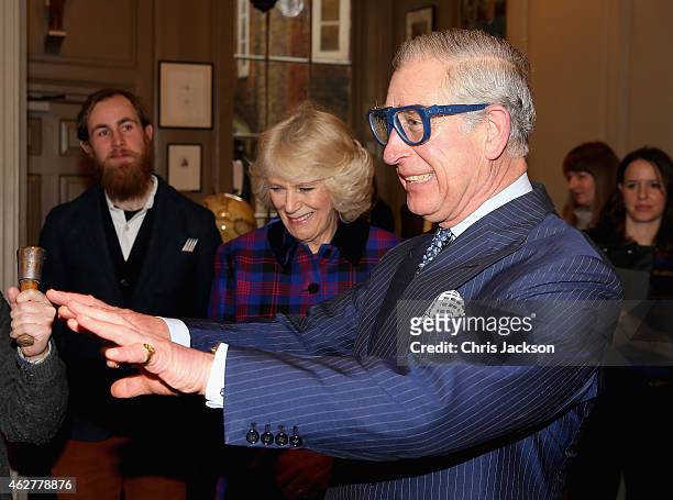 Prince Charles, Prince of Wales jokes that he can't see in a pair of safety goggles as Camilla, Duchess of Cornwall laughs before he tries some...