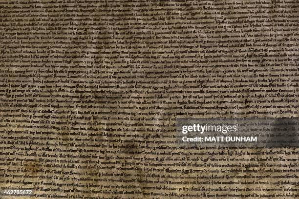 Lines of manuscript text are seen through a glass cabinet on the Salisbury Cathedral 1215 copy of the Magna Carta as it is on display with the three...