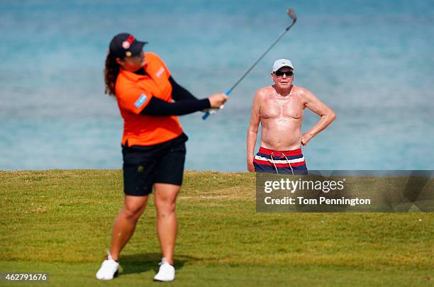 Beachgoer looks on as Ariya Jutanugarn of Thailand hits a shot on the eighth hole during round one of the Pure Silk Bahamas LPGA Classic at the Ocean...