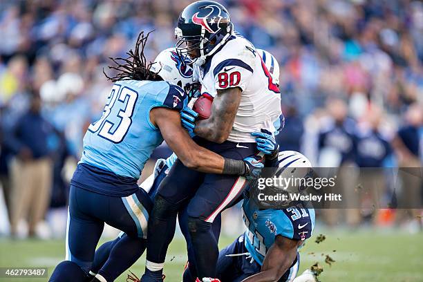 Andre Johnson of the Houston Texans is tackled by Michael Griffin and Bernard Pollard of the Tennessee Titans at LP Field on December 29, 2013 in...