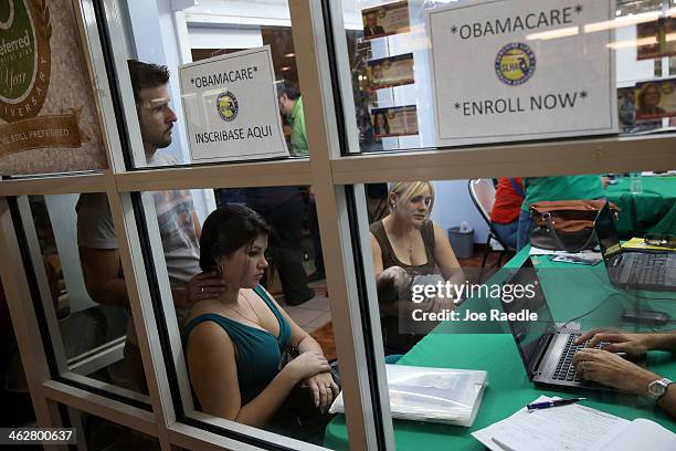 Ronnie Cabrera, Dailem Delombard and Maylin Lezcano holding Lucas Cabrera sit with an insurance agent from Sunshine Life and Health Advisors as they...