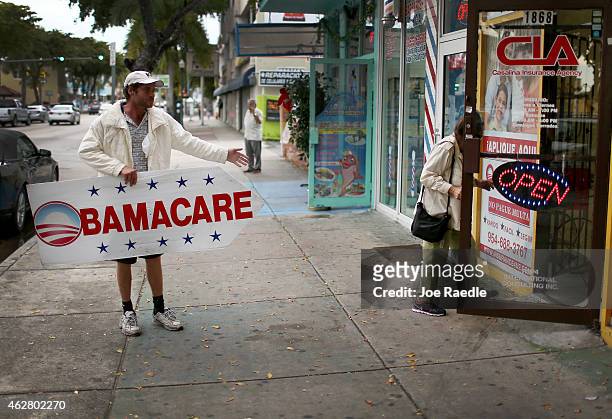 Pedro Rojas holds a sign directing people to an insurance company where they can sign up for the Affordable Care Act, also known as Obamacare, before...