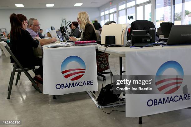 Aymara Marchante and Wiktor Garcia sit with Maria Elena Santa Coloma, an insurance advisor with UniVista Insurance company, as they sign up for the...