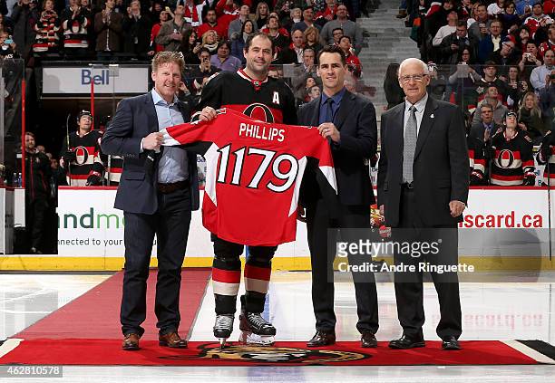 Chris Phillips of the Ottawa Senators is presented with a special jersey in his franchise record breaking 1179th game with the team, by former...