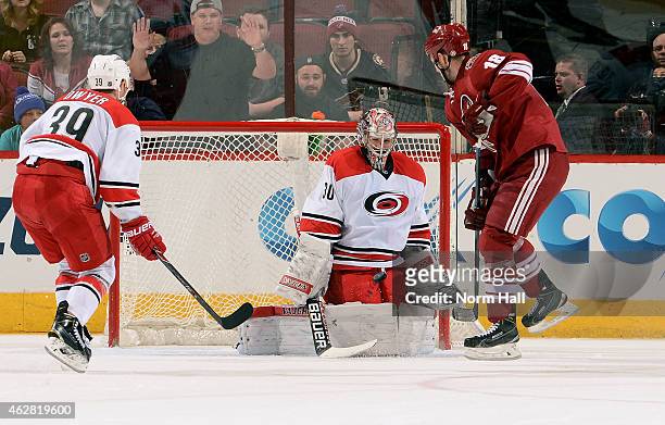 Cam Ward of the Carolina Hurricanes makes a save in front of David Moss of the Arizona Coyotes as Patrick Dwyer of the Hurricanes skates in during...