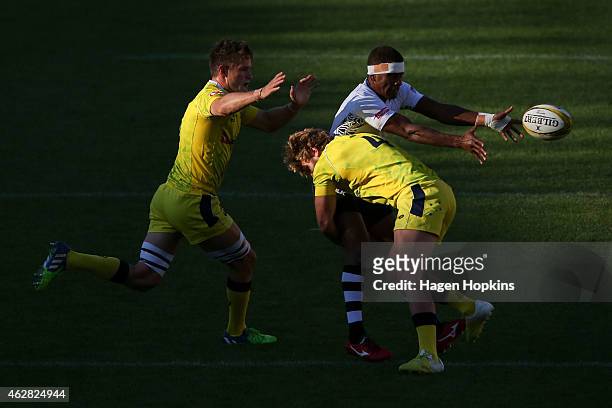 Emosi Mulevoro of Fiji passes under pressure from Con Foley and Lewis Holland of Australia during the match between Australia and Fiji in the 2015...
