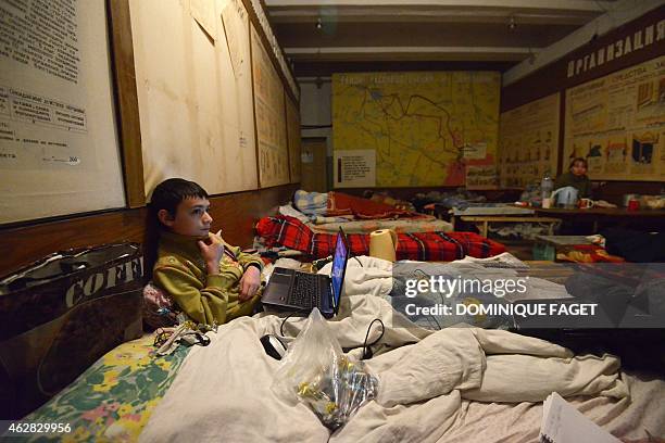 Artium, 10-years-old, sits in a bed with his laptop as he and others wait for the end of the shelling in Donetsk's Petrovski district, in the eastern...