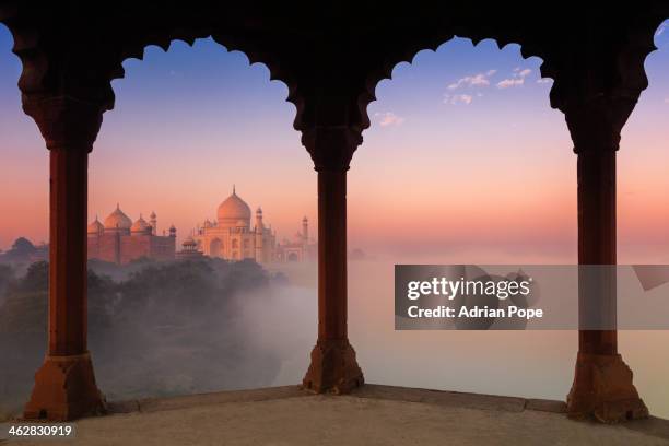 taj mahal in fog framed by arches - indien stock-fotos und bilder