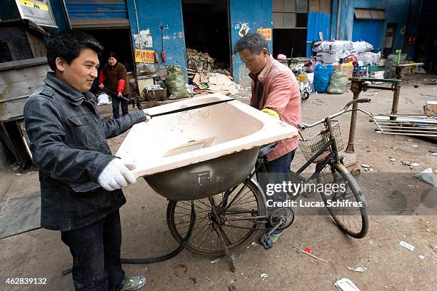 April 8: Yan Wei and another garbage recycler bring a trashed bathtub to a recycling center on April 8, 2010 in Shanghai, China. The bathtub weighs...