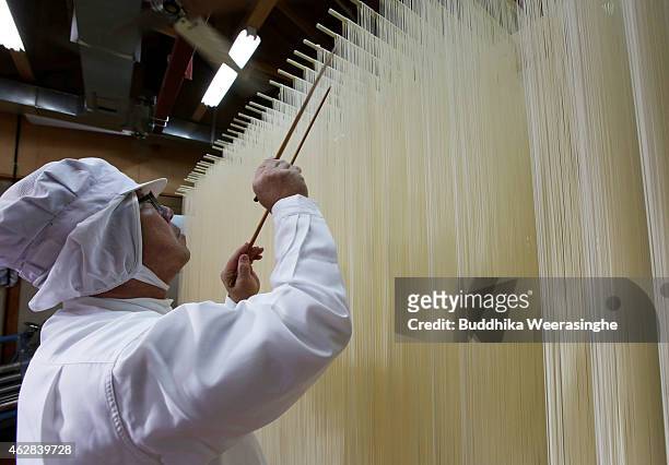 Japanese somen maker, Yoshinobu Izuhara, uses chopsticks to stretch drying Ibonoito somen noodles on February 6, 2015 in Tatsuno, Japan. Somen is a...
