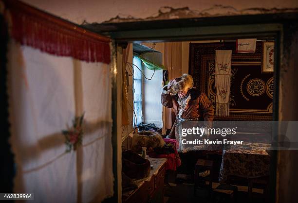 Chinese Kazakh eagle hunter Margars Mazkin, 74 years, puts on his traditional clothing before leaving for competition on January 31, 2015 in the...