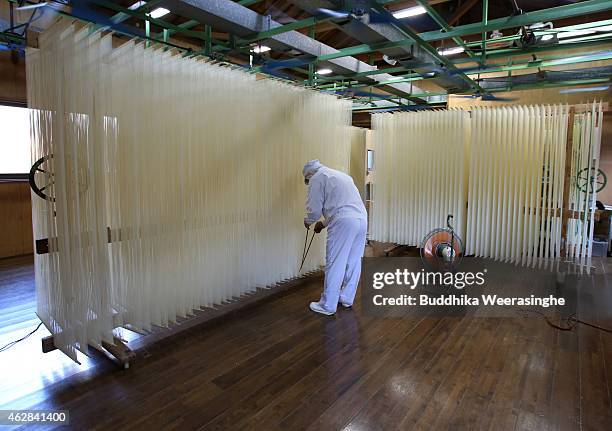 Japanese somen maker, Yoshinobu Izuhara, uses chopsticks to stretch drying Ibonoito somen noodles on February 6, 2015 in Tatsuno, Japan. Somen is a...