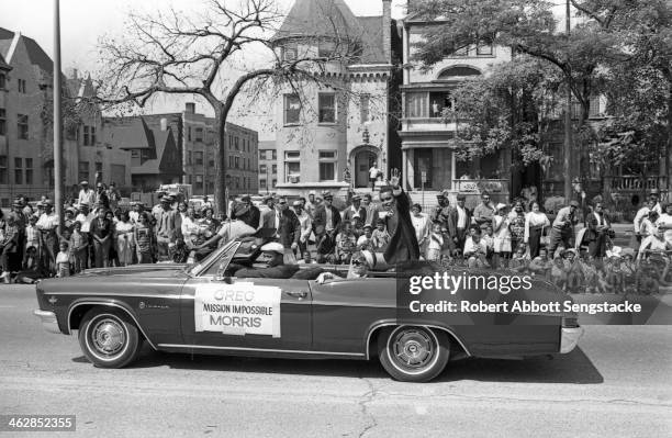 Actor Greg Morris, star of the television show 'Mission Impossible', waves to the crowds while riding an open convertible during the Bud Billiken Day...