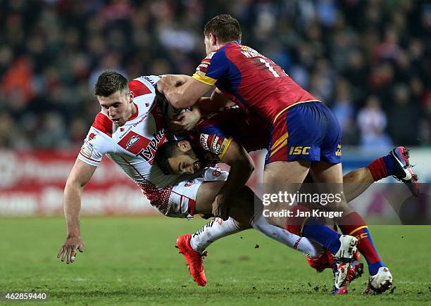 Joe Greenwood of St Helens is dumped by Eloi Pelissier and Elliott Whitehead of Catalans Dragons during the First Utility Super League match between...