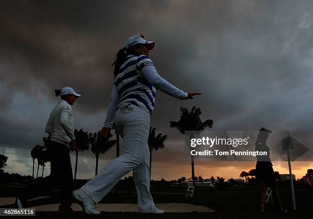 Azahara Munoz of Spain, Inbee Park of South Korea and Paula Creamer wals off the 15th hole after play was suspended due to darkness during round two...
