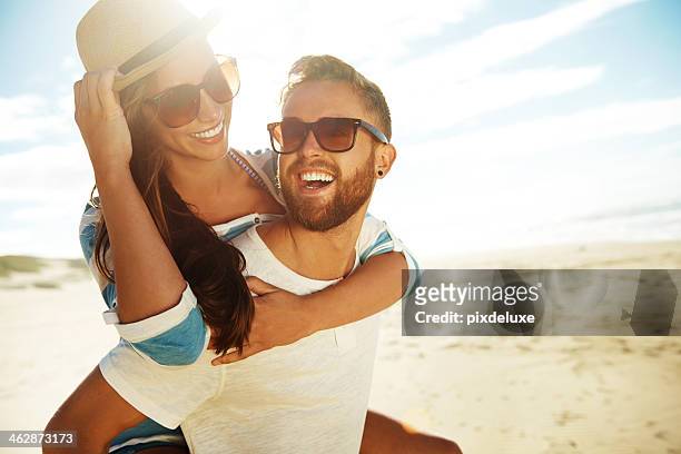 piggyback couple at beach - couple on beach sunglasses stockfoto's en -beelden