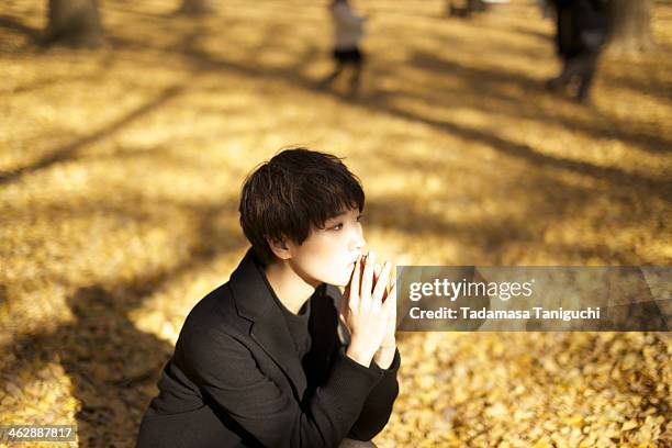 japanese woman sitting in a nature - schwarzer mantel stock-fotos und bilder