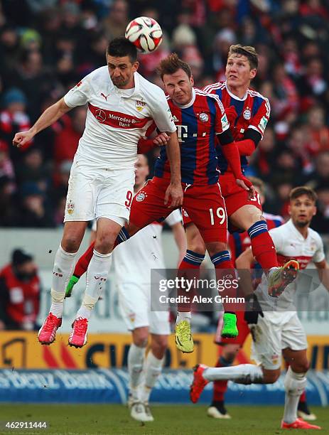 Vedad Ibisevic of Stuttgart jumps for a header with Mario Goetze and Bastian Schweinsteiger of Muenchen during the Bundesliga match between VfB...