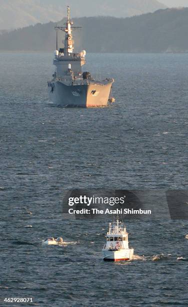 In this aerial image, the overturned boat is being pulled by a Japan Coast Guard ship with the collided vessel "Osumi" in the background on January...