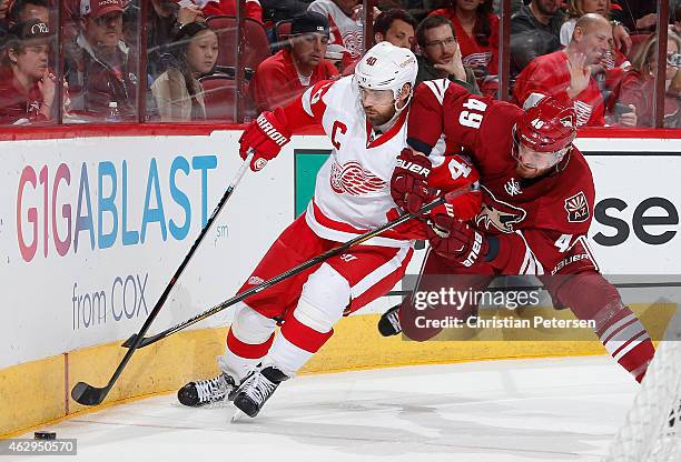 Henrik Zetterberg of the Detroit Red Wings battles with Alex Bolduc of the Arizona Coyotes as he attempts to control the puck during the third period...