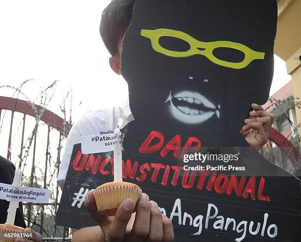 Filipino protester holds a cupcake candle and a shadow cut-out of President Benigno Aquino III near Malacanang presidential palace, a day before the...