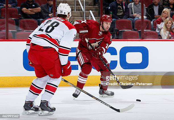 Kyle Chipchura of the Arizona Coyotes passes the puck around Alexander Semin of the Carolina Hurricanes during the NHL game at Gila River Arena on...