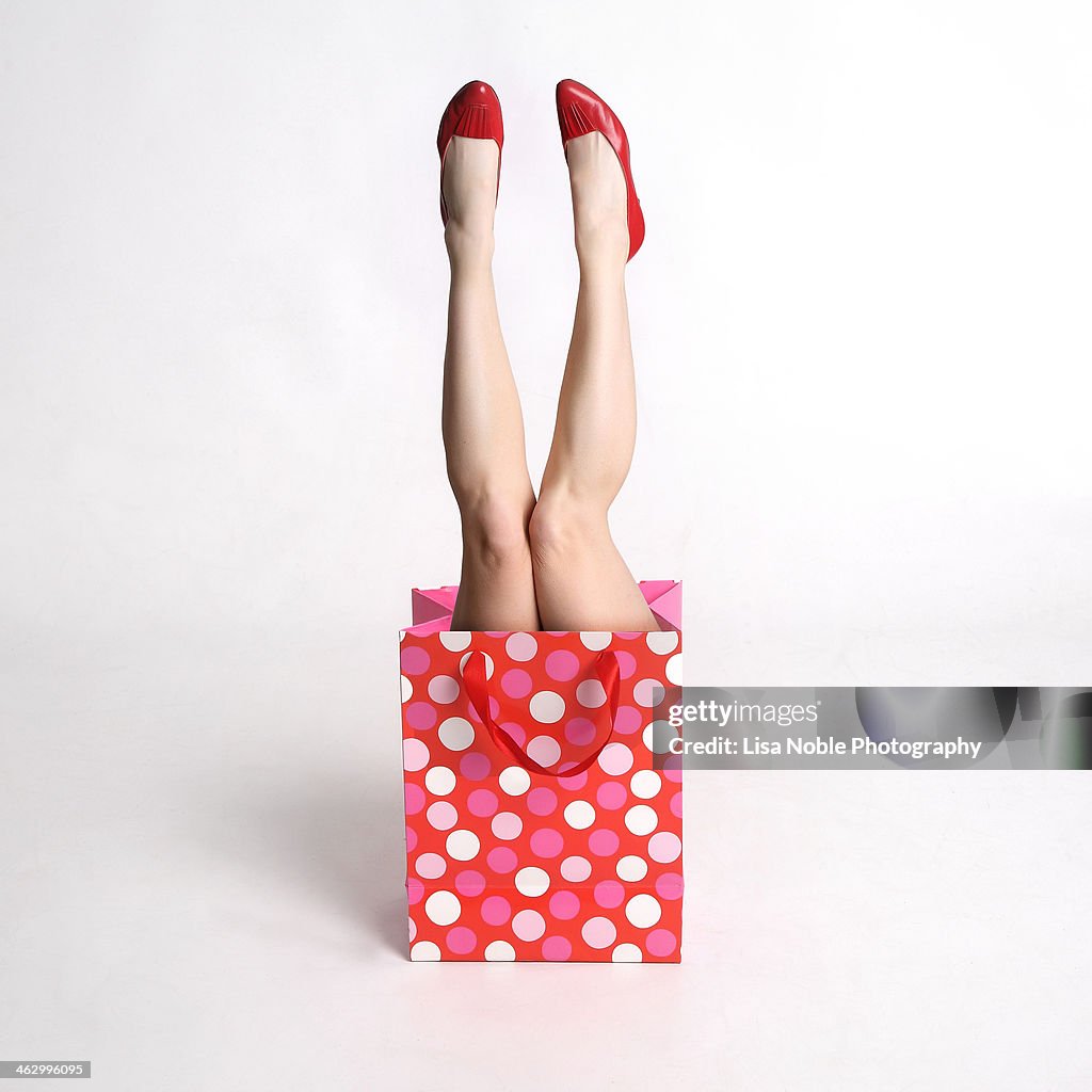 Woman's legs coming out of a festive gift  bag