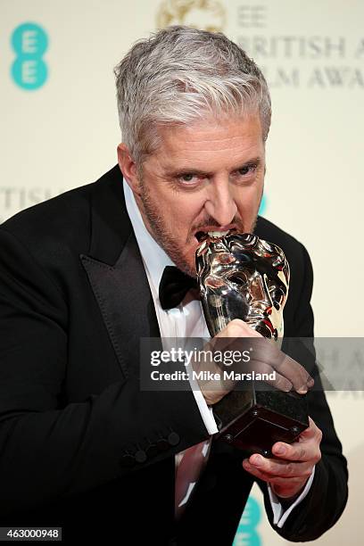 Anthony McCarten, winner of the Best Adapted Screenplay award for the movie 'The Theory Of Everything' poses in the winners room at the EE British...