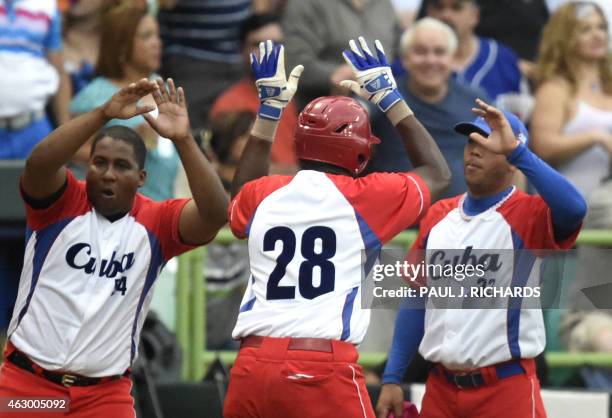 Cuba National baseball team infielder William Saavedra receives high fives from teammates Alfredo Despaigne and Yadiel Hernandez after scoring in the...