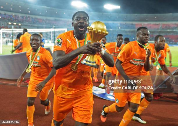 Ivory Coast's defender Kolo Toure raises the trophy as he celebrates after winning the 2015 African Cup of Nations final football match between Ivory...