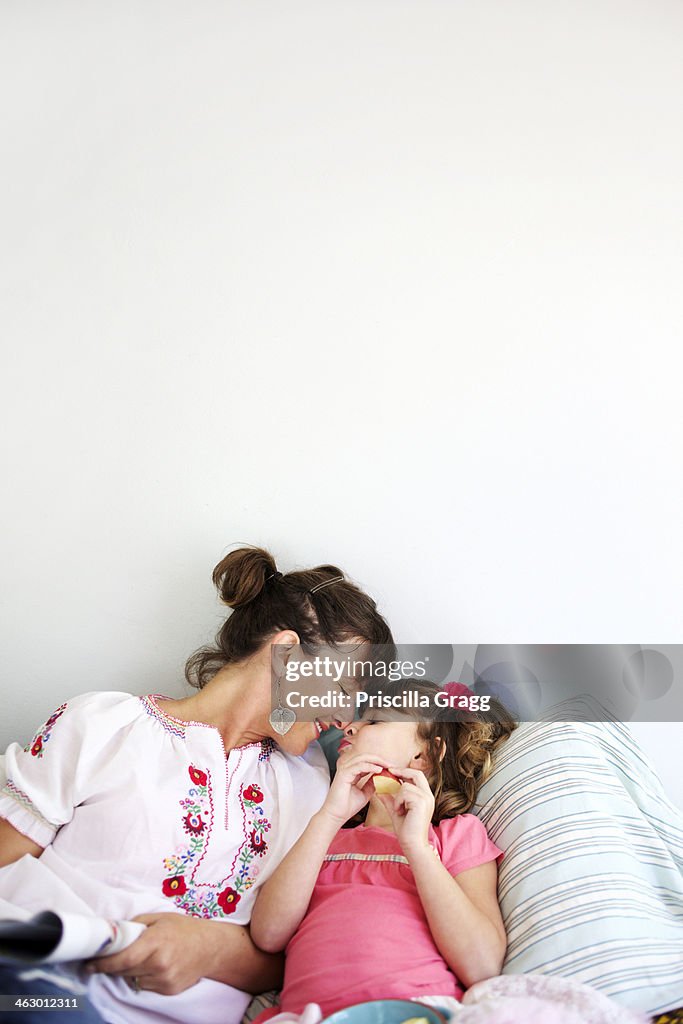 Mother and daughter relaxing on bed