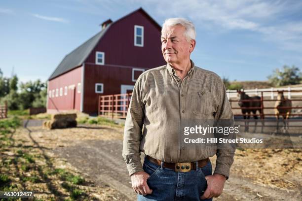 caucasian rancher standing near barn - three quarter length stockfoto's en -beelden