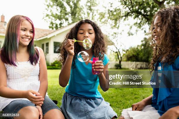 girls blowing bubbles in backyard - afrikanisches kind beobachtet natur stock-fotos und bilder