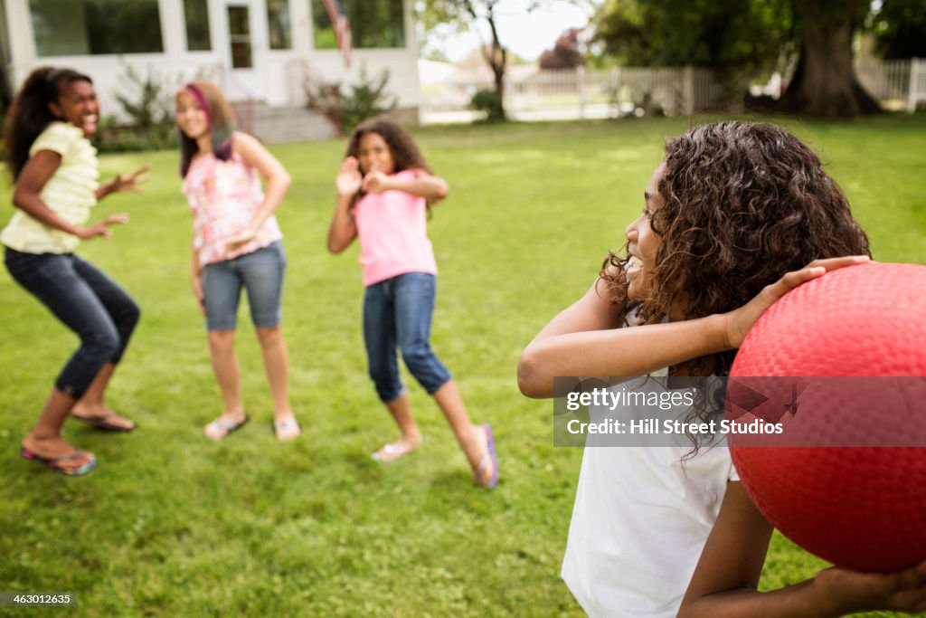 Girls playing dodgeball in backyard