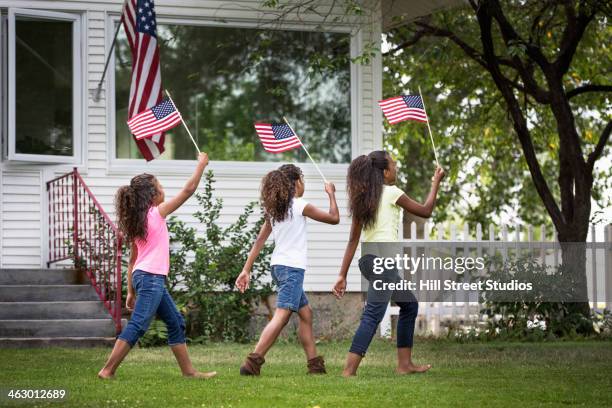 mixed race girls marching with american flags - america parade stockfoto's en -beelden