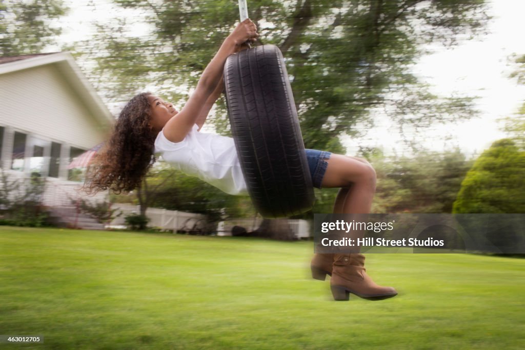 Mixed race girl playing on tire swing